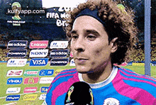a soccer player wearing a headband is talking into a microphone on a soccer field