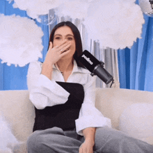 a woman sits on a couch with a podimo microphone