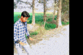 a young man in a plaid shirt is standing in a field with trees in the background
