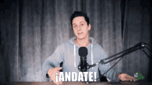 a man stands in front of a microphone with the words andate written on the bottom