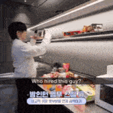 a man standing in a kitchen looking at a box that says " who hired this guy "