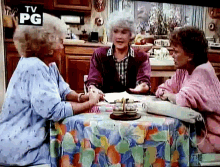 three older women are sitting at a table with a tv pg logo above them