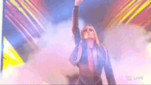 a woman is standing on a stage with her hand up in the air .