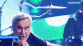 a man in a tuxedo singing into a microphone with vkfest in the upper right corner