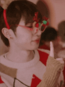 a young man wearing a headband and glasses is giving a thumbs up sign .