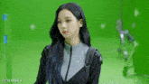 a woman with long blue hair is standing in front of a green screen .