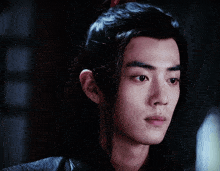 a close up of a young man 's face with a ponytail