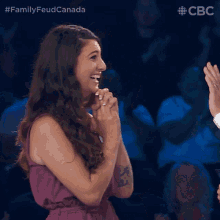 a woman in a purple dress applauds while a man in a suit gives her a high five