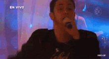 a man is singing into a microphone with the words en vivo behind him