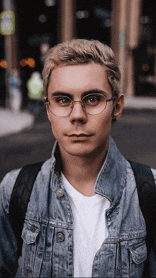 a man wearing glasses and a denim jacket