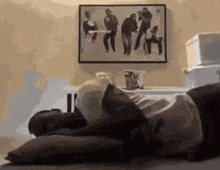 a man is laying on a bed with a pillow and a picture on the wall behind him .