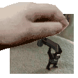 a hand is holding a toy gun over a miniature figure .