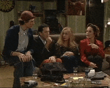 a group of people sitting on a couch with a dart board behind them that says ' a ' on it
