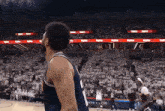 a basketball player with the number 11 on his jersey stands on the court in front of a crowd