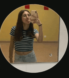 a woman taking a picture of herself in a mirror with her phone