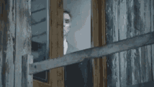 a man in a bow tie is peeking out of a window .