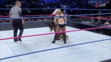 two women are wrestling in a wrestling ring with a referee