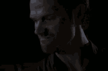 a man with a beard is looking at the camera in the dark