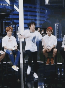 a group of young men are sitting in chairs and one of them is dancing in front of them .