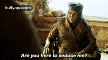 an older woman is sitting in a chair and talking to someone .