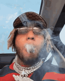 a man wearing glasses and a gucci hat is smoking a cigar