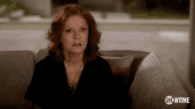 a woman with red hair is sitting on a couch with showtime written on the bottom of the screen .