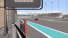a red car is driving down a race track with a sign behind it that says dubai uae