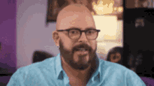 a bald man with a beard wearing glasses and a blue shirt