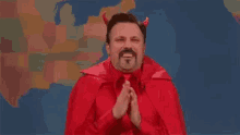 a man dressed as a devil with horns is praying with his hands together .