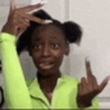 a young girl in a neon green jacket is giving the middle finger .