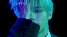 a man in a suit and tie is covering his face with his hand in a dark room .