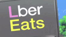 a sign that says uber eats in pink and yellow letters
