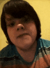 a young boy with long hair is wearing a striped shirt and making a funny face