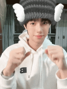 a boy wearing a white hoodie and a black hat with a letter b on it