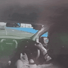 a man is driving a car with a rear view mirror visible