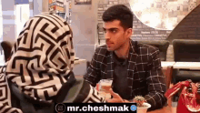 a man and a woman are sitting at a table and talking to each other .