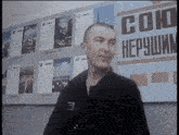 a man stands in front of a sign that says ' союз нерушим ' on it