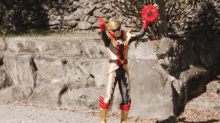 a man in a gold and red costume is holding a red object in his hands