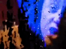 a blurry picture of a man 's face with blue lights behind him