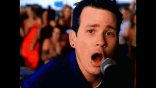 a man singing into a microphone with a crowd of people behind him