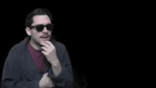 a man wearing sunglasses and a robe is thinking about a silly question to ask