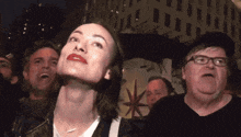 a woman with red lips looks up at the sky while a man with glasses looks down