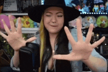 a woman wearing a hat is making a funny face with her hands outstretched