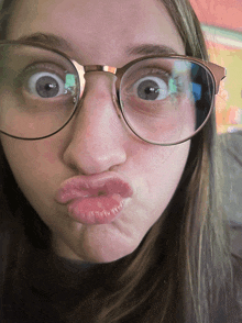 a girl wearing glasses makes a funny face with her lips