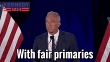 a man in a suit and tie is giving a speech in front of an american flag with the words kennedy 2024 behind him