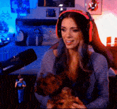 a woman wearing headphones is holding a small brown dog in front of a shure microphone