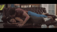 a man and a woman are laying on a couch and kissing .