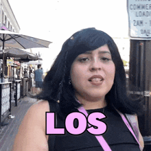 a woman wearing a black top and a pink purse has the word los on her chest