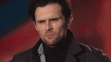 a man with a beard is wearing a turtleneck and a black jacket