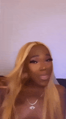 a woman with long blonde hair is blowing a kiss while wearing a wig and a necklace .